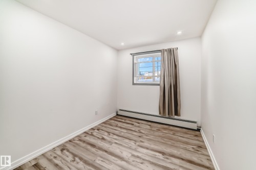 Spare room featuring a baseboard radiator, light wood-type flooring, and recessed lighting - 4B 13230 Fort Road, Edmonton, AB - Indoor Photo Showing Other Room
