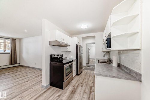 Kitchen with open shelves, appliances with stainless steel finishes, white cabinets, under cabinet range hood, and light wood-style floors - 4B 13230 Fort Road, Edmonton, AB - Indoor Photo Showing Kitchen