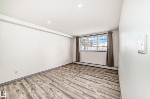 Empty room featuring light wood-style flooring, a baseboard heating unit, and recessed lighting - 4B 13230 Fort Road, Edmonton, AB - Indoor Photo Showing Other Room