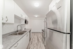 Kitchen with appliances with stainless steel finishes, white cabinets, light wood-style floors, light countertops, and tasteful backsplash - 