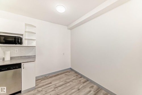 Kitchen with open shelves, stainless steel dishwasher, light wood-type flooring, white cabinets, and black microwave - 4B 13230 Fort Road, Edmonton, AB - Indoor