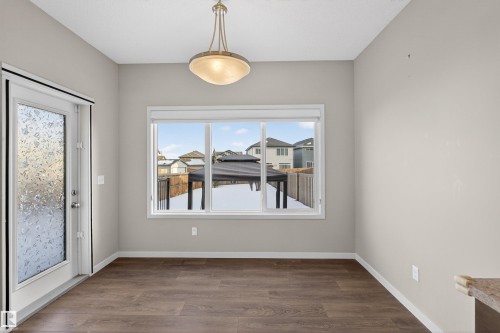 Unfurnished dining area featuring dark wood-style flooring and baseboards - 4723 Alwood Bend Bend Sw, Edmonton, AB - Indoor Photo Showing Other Room