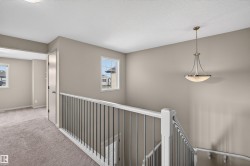 Hall featuring an upstairs landing, carpet flooring, and a textured ceiling - 