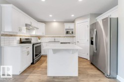 Kitchen featuring stainless steel appliances, white cabinetry, a center island, under cabinet range hood, and light wood-type flooring - 