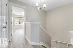 Corridor featuring an upstairs landing, light wood-style flooring, and a chandelier - 