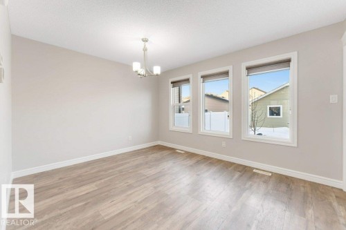 Empty room with a chandelier, light wood-style floors, and a textured ceiling - 1423 24 Street, Edmonton, AB - Indoor Photo Showing Other Room