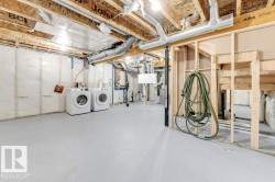 Unfinished basement featuring washer and clothes dryer and electric panel - 