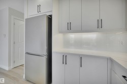 Kitchen featuring freestanding refrigerator, light stone countertops, light wood-style floors, and modern cabinets - 