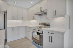 Kitchen with electric range, under cabinet range hood, light wood-style flooring, white cabinetry, and recessed lighting - 