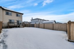 Snowy yard featuring a fenced backyard, a deck, and a residential view - 