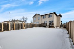Snow covered property featuring a fenced backyard, a chimney, a deck, and a gate - 