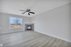 Unfurnished living room with a tiled fireplace, light wood-style flooring, and ceiling fan - 