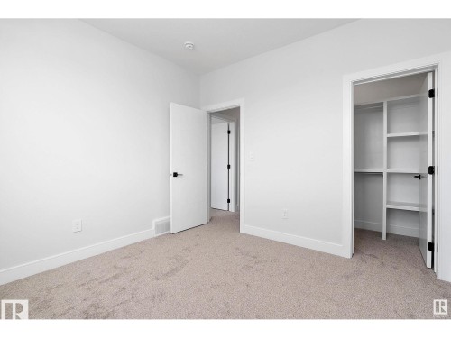 Unfurnished bedroom featuring a spacious closet and light colored carpet - 138 South Ravines Drive, Devon, AB - Indoor