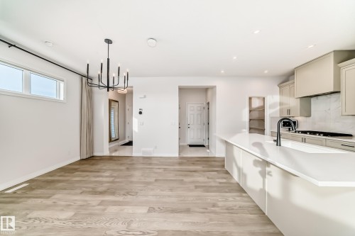 Kitchen with a chandelier, hanging light fixtures, light wood-style flooring, decorative backsplash, and recessed lighting - 3249 Dixon Way, Edmonton, AB - Indoor Photo Showing Kitchen