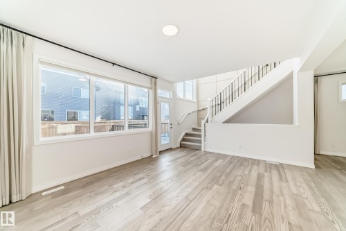 Unfurnished living room with stairway and light wood-style floors - 3249 Dixon Way, Edmonton, AB - Indoor Photo Showing Other Room