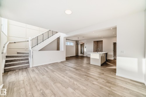 Unfurnished living room with recessed lighting, light wood finished floors, stairs, and a chandelier - 3249 Dixon Way, Edmonton, AB - Indoor Photo Showing Other Room