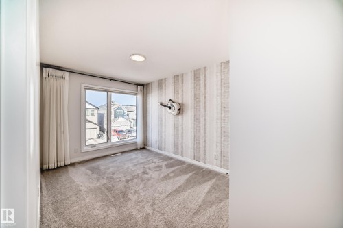 Empty room with light carpet and wallpapered walls - 3249 Dixon Way, Edmonton, AB - Indoor Photo Showing Other Room