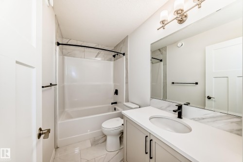 Bathroom featuring vanity, shower / bath combination, and light marble finish floors - 3249 Dixon Way, Edmonton, AB - Indoor Photo Showing Bathroom