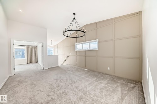Unfurnished dining area featuring a decorative wall, light carpet, and a chandelier - 3249 Dixon Way, Edmonton, AB - Indoor Photo Showing Other Room