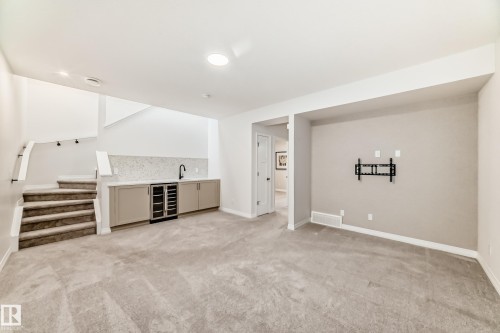 Indoor wet bar featuring wine cooler, light colored carpet, and stairs - 3249 Dixon Way, Edmonton, AB - Indoor Photo Showing Other Room