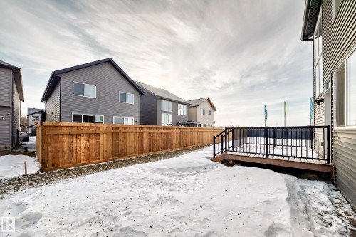 Yard layered in snow featuring a wooden deck and a residential view - 3249 Dixon Way, Edmonton, AB - Outdoor With Exterior