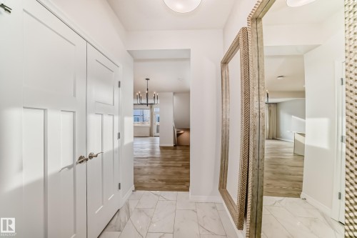 Corridor with a chandelier and light marble finish floors - 3249 Dixon Way, Edmonton, AB - Indoor Photo Showing Other Room