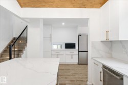 Kitchen with light stone countertops, white cabinetry, stainless steel appliances, light wood-type flooring, and recessed lighting - 