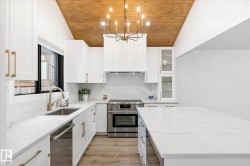 Kitchen with decorative light fixtures, wood ceiling, white cabinets, appliances with stainless steel finishes, and light stone counters - 