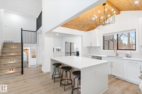 Kitchen featuring high vaulted ceiling, a wooden ceiling with exposed beams, white cabinets, a breakfast bar area, and light wood-type flooring - 38 Woodcrest Avenue, St. Albert, AB - Indoor Photo Showing Kitchen With Upgraded Kitchen