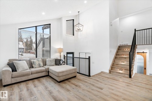 Living area with light wood-style floors, a towering ceiling, a chandelier, recessed lighting, and stairs - 38 Woodcrest Avenue, St. Albert, AB - Indoor Photo Showing Living Room