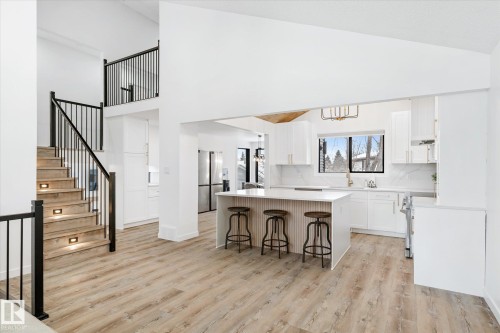 Kitchen featuring a breakfast bar area, appliances with stainless steel finishes, a center island, light wood-type flooring, and white cabinetry - 38 Woodcrest Avenue, St. Albert, AB - Indoor Photo Showing Kitchen