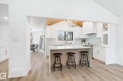 Kitchen featuring lofted ceiling, a breakfast bar, a center island, pendant lighting, and white cabinets - 