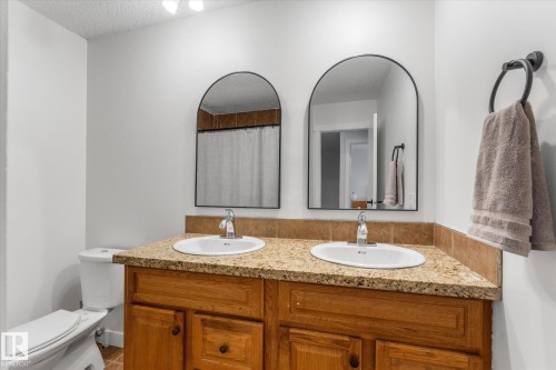 Full bathroom featuring double vanity, a shower with curtain, and a textured ceiling - 289 Grandin Village, St. Albert, AB - Indoor Photo Showing Bathroom