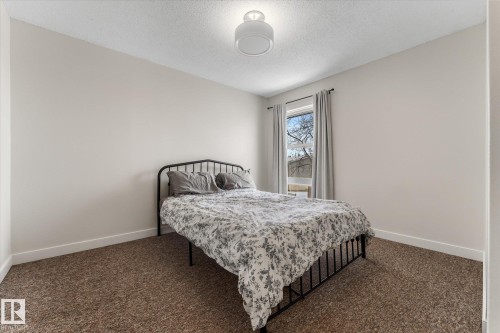 Carpeted bedroom with baseboards and a textured ceiling - 289 Grandin Village, St. Albert, AB - Indoor Photo Showing Bedroom
