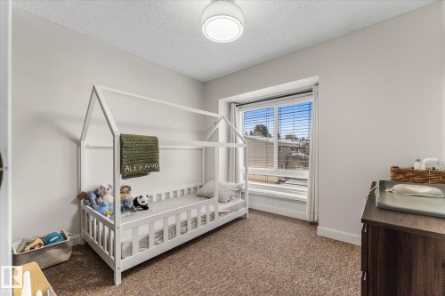 Carpeted bedroom featuring a textured ceiling and baseboards - 289 Grandin Village, St. Albert, AB - Indoor Photo Showing Bedroom
