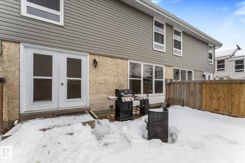 Snow covered back of property with french doors and stucco siding - 289 Grandin Village, St. Albert, AB - Outdoor With Exterior