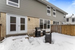 Snow covered back of property with french doors and stucco siding - 