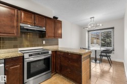 Kitchen featuring stainless steel appliances, a peninsula, under cabinet range hood, tasteful backsplash, and a textured ceiling - 