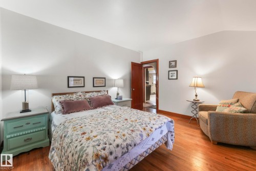 Bedroom featuring dark wood-type flooring, vaulted ceiling, and arched walkways - 5043 48 St, Sylvan Lake, AB - Indoor Photo Showing Bedroom