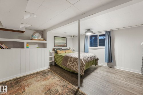 Bedroom with light wood-style flooring and wooden walls - 5043 48 St, Sylvan Lake, AB - Indoor Photo Showing Bedroom
