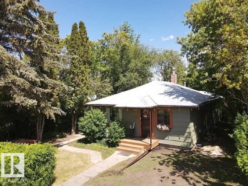 Bungalow-style home featuring view of wooded area and a chimney - 5043 48 St, Sylvan Lake, AB - Outdoor