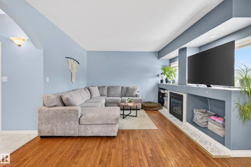 Living room with arched walkways, a glass covered fireplace, and wood finished floors - 24 Olmstead Court, St. Albert, AB - Indoor Photo Showing Living Room With Fireplace