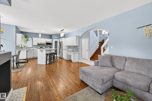 Living room with stairway, light wood finished floors, and arched walkways - 24 Olmstead Court, St. Albert, AB - Indoor Photo Showing Living Room
