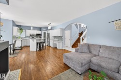 Living room with stairway, light wood finished floors, and arched walkways - 