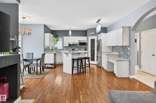 Kitchen featuring light countertops, light wood finished floors, arched walkways, and a breakfast bar area - 24 Olmstead Court, St. Albert, AB - Indoor