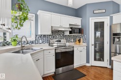 Kitchen featuring stainless steel appliances, white cabinets, light countertops, and under cabinet range hood - 