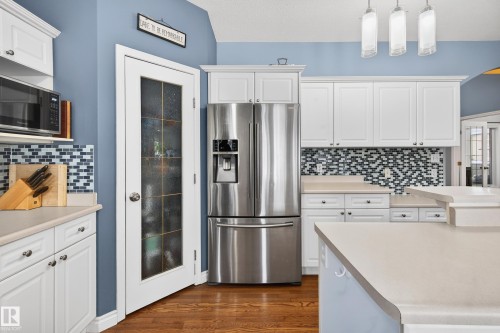 Kitchen with stainless steel refrigerator with ice dispenser, white cabinets, and light countertops - 24 Olmstead Court, St. Albert, AB - Indoor Photo Showing Kitchen With Upgraded Kitchen