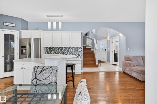 Kitchen featuring a breakfast bar, stainless steel refrigerator with ice dispenser, white cabinets, and open floor plan - 24 Olmstead Court, St. Albert, AB - Indoor Photo Showing Kitchen
