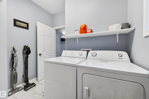 Laundry area featuring washer and dryer and light marble finish flooring - 24 Olmstead Court, St. Albert, AB - Indoor Photo Showing Laundry Room