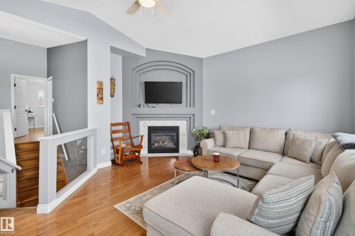 Living area featuring a tile fireplace, light wood finished floors, vaulted ceiling, and a ceiling fan - 24 Olmstead Court, St. Albert, AB - Indoor Photo Showing Living Room With Fireplace